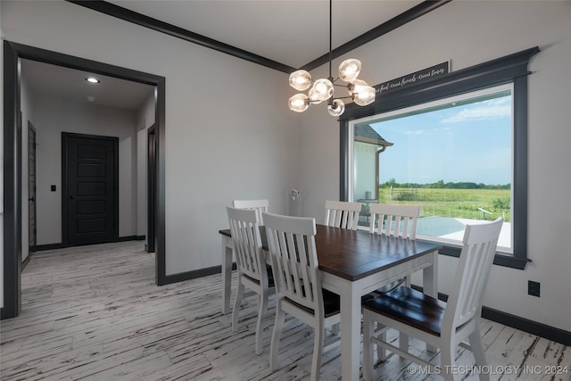 dining space featuring light wood-style floors, baseboards, a chandelier, and crown molding