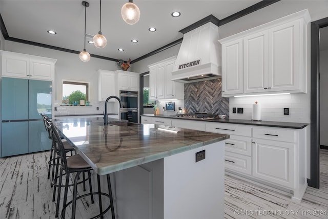 kitchen featuring white cabinets, a spacious island, custom range hood, stainless steel appliances, and pendant lighting