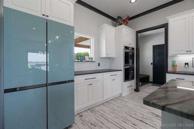 kitchen featuring backsplash, white cabinets, stainless steel double oven, and fridge