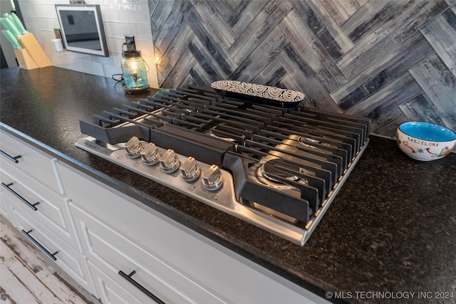 details featuring tasteful backsplash, white cabinets, and stainless steel gas cooktop