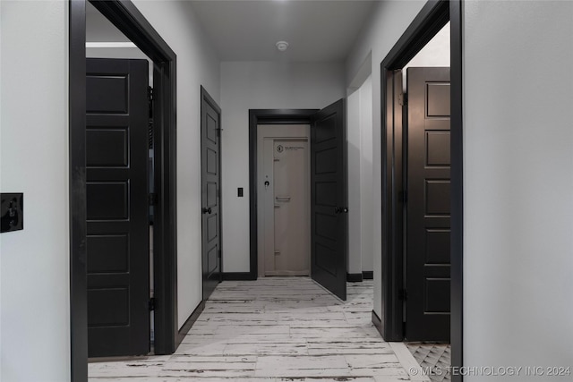 corridor featuring light wood-style flooring and baseboards