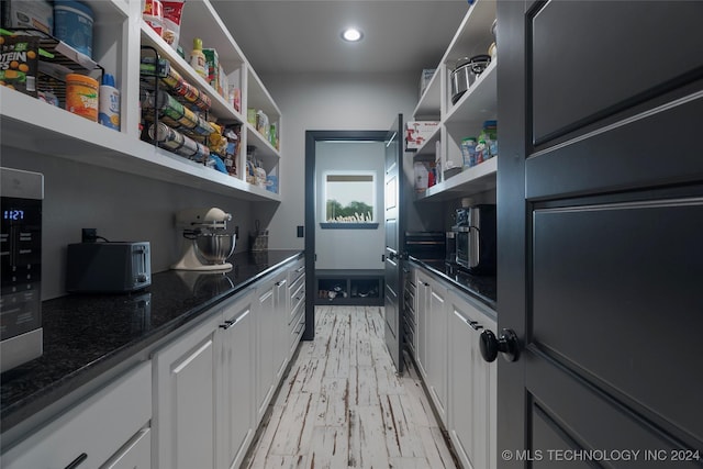 kitchen featuring white cabinetry, dark stone counters, and light hardwood / wood-style flooring