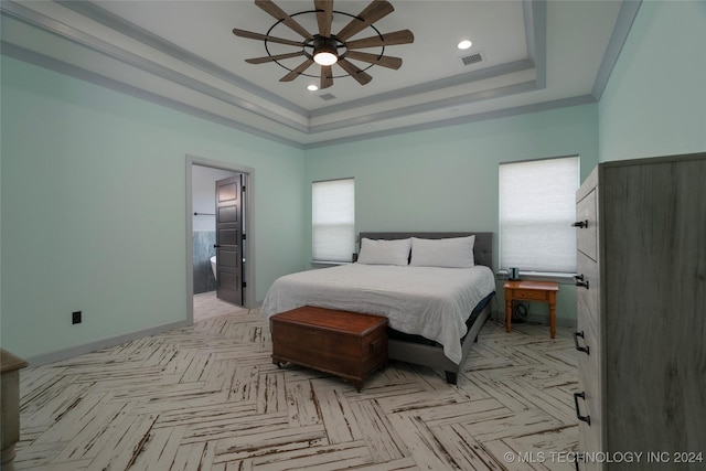 bedroom with ceiling fan, connected bathroom, visible vents, baseboards, and a raised ceiling