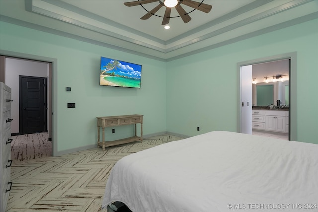 bedroom featuring ceiling fan, light parquet floors, a raised ceiling, and ensuite bath