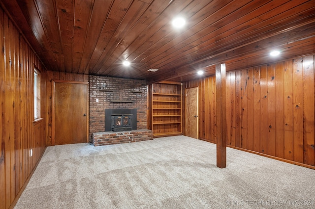 basement with wood walls, wooden ceiling, and a fireplace