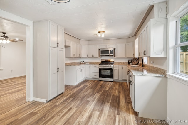 kitchen featuring dark hardwood / wood-style flooring, appliances with stainless steel finishes, ceiling fan, light stone counters, and white cabinets