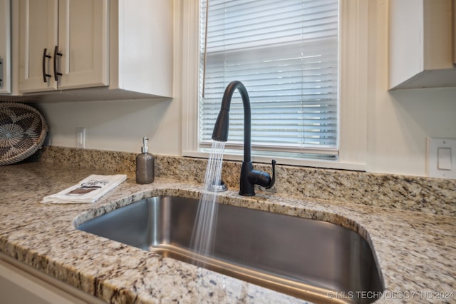 details featuring light stone counters, sink, and white cabinets