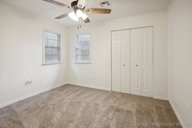 unfurnished bedroom featuring ornamental molding, a closet, ceiling fan, and carpet flooring