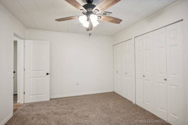 unfurnished bedroom featuring two closets, ceiling fan, ornamental molding, and carpet floors