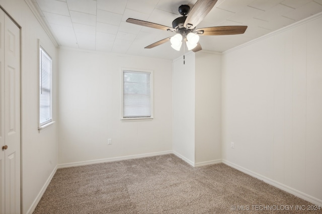 carpeted spare room featuring crown molding and ceiling fan