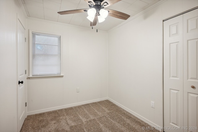 carpeted empty room with ceiling fan and crown molding