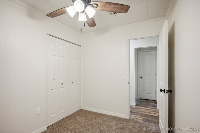 unfurnished bedroom featuring a closet, ceiling fan, crown molding, and carpet floors