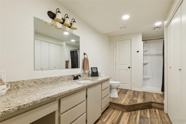 full bath with wood finished floors, visible vents, toilet, vanity, and walk in shower