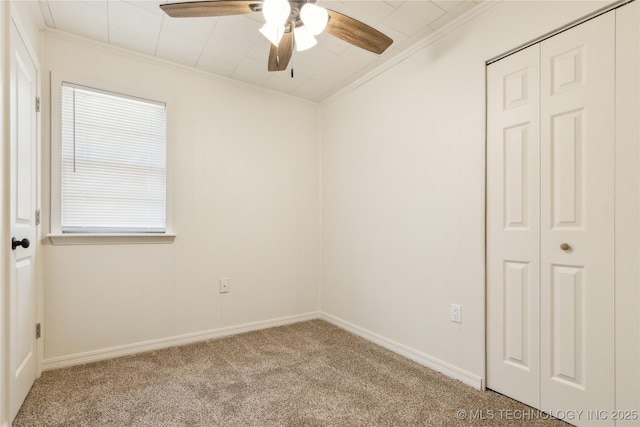 spare room with crown molding, carpet flooring, baseboards, and ceiling fan