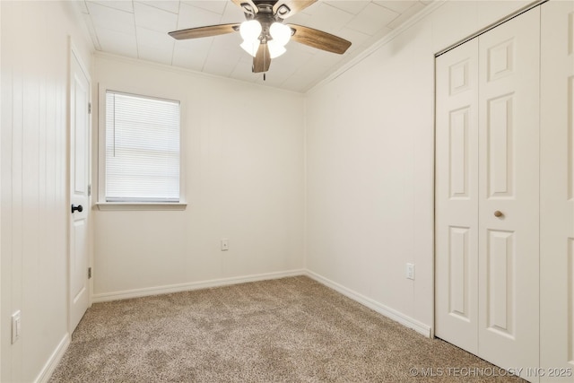 empty room with baseboards, a ceiling fan, carpet flooring, and crown molding
