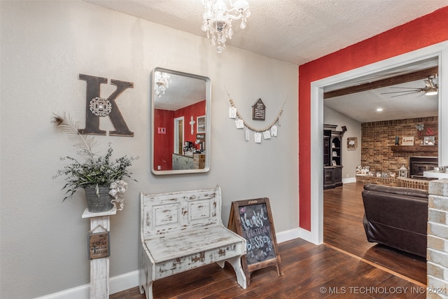 hallway with dark hardwood / wood-style floors, an inviting chandelier, brick wall, and a textured ceiling