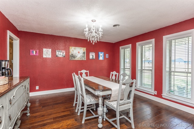 dining space with a wealth of natural light, dark wood-type flooring, a textured ceiling, and an inviting chandelier