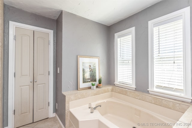 bathroom with a tub to relax in and tile patterned floors