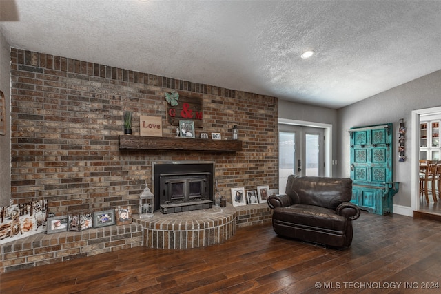 living room featuring french doors, dark hardwood / wood-style floors, a textured ceiling, and a fireplace