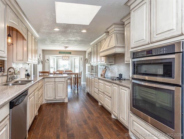 kitchen featuring sink, appliances with stainless steel finishes, dark wood-type flooring, premium range hood, and pendant lighting