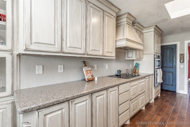 kitchen featuring black electric stovetop, dark wood-type flooring, a skylight, custom exhaust hood, and a textured ceiling