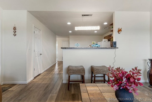 kitchen with a kitchen breakfast bar, dark wood-type flooring, hanging light fixtures, white fridge, and kitchen peninsula