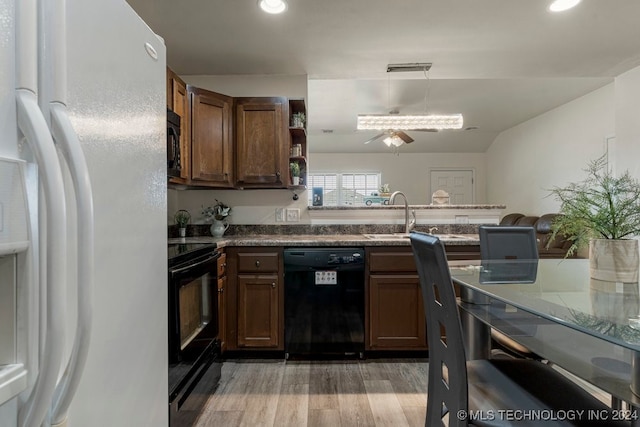 kitchen with decorative light fixtures, light hardwood / wood-style floors, stone countertops, ceiling fan, and black appliances