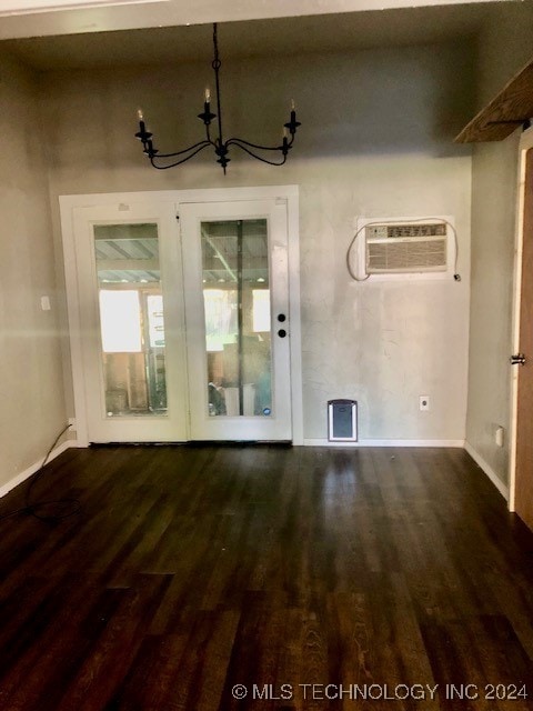 interior space featuring dark wood-type flooring, an AC wall unit, and a chandelier