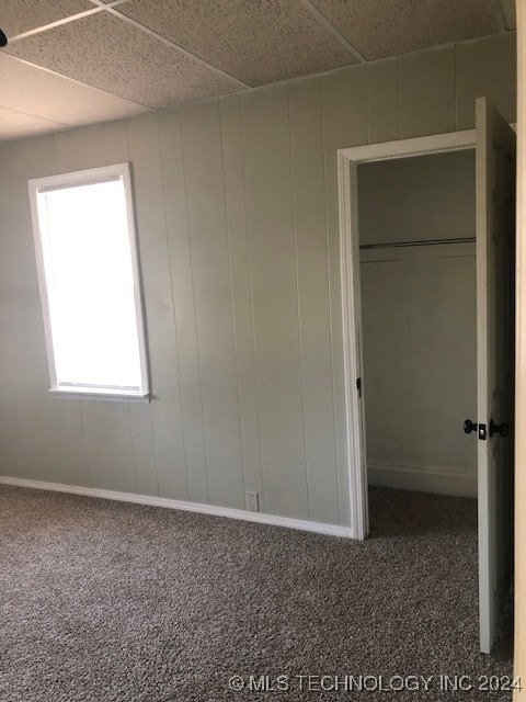 unfurnished bedroom with a drop ceiling and carpet floors