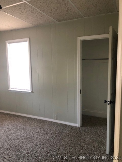 unfurnished bedroom featuring a closet, carpet, and a drop ceiling