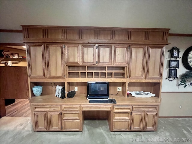 office area featuring built in desk, light carpet, and ornamental molding