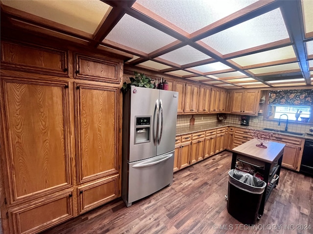 kitchen featuring decorative backsplash, coffered ceiling, dark wood-type flooring, sink, and stainless steel fridge