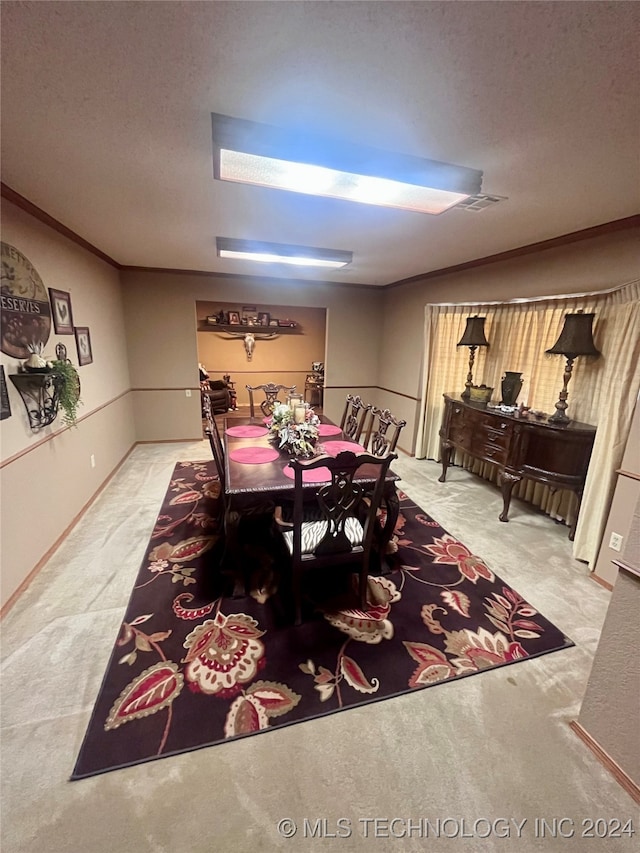 carpeted dining room with ornamental molding and a textured ceiling