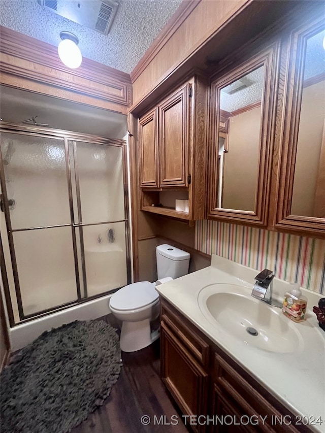 bathroom featuring a shower with door, a textured ceiling, wood-type flooring, toilet, and vanity