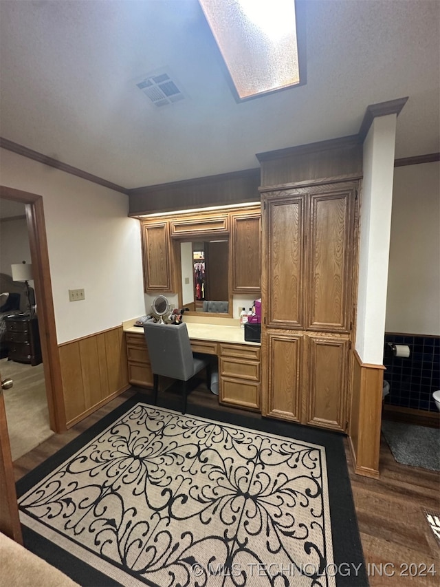 office space featuring built in desk, dark wood-type flooring, crown molding, and a skylight