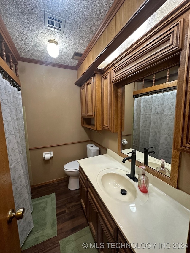 bathroom featuring toilet, wood-type flooring, ornamental molding, vanity, and a textured ceiling