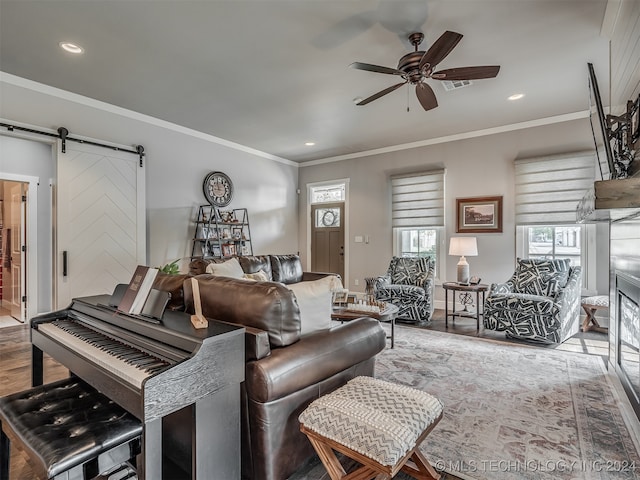 living room featuring ceiling fan, a barn door, wood-type flooring, and a wealth of natural light