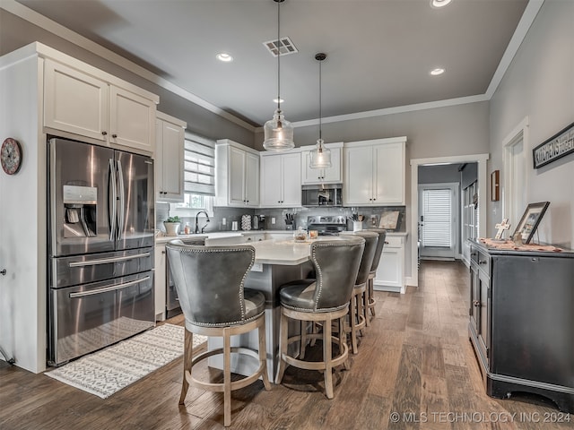 kitchen featuring appliances with stainless steel finishes, dark hardwood / wood-style flooring, decorative light fixtures, a center island, and white cabinetry