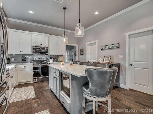 kitchen featuring white cabinets, decorative light fixtures, a breakfast bar area, and appliances with stainless steel finishes