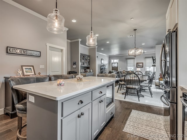 kitchen featuring a center island, dark wood-type flooring, hanging light fixtures, a kitchen breakfast bar, and appliances with stainless steel finishes