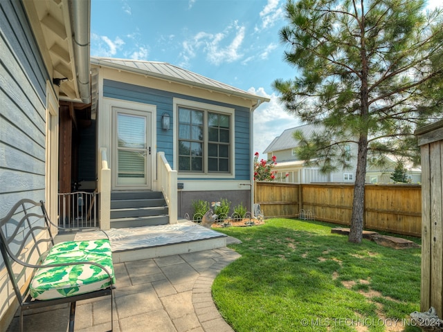 entrance to property featuring a lawn and a patio area