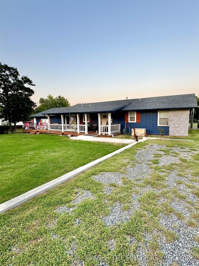 view of front facade with a yard, covered porch, and driveway