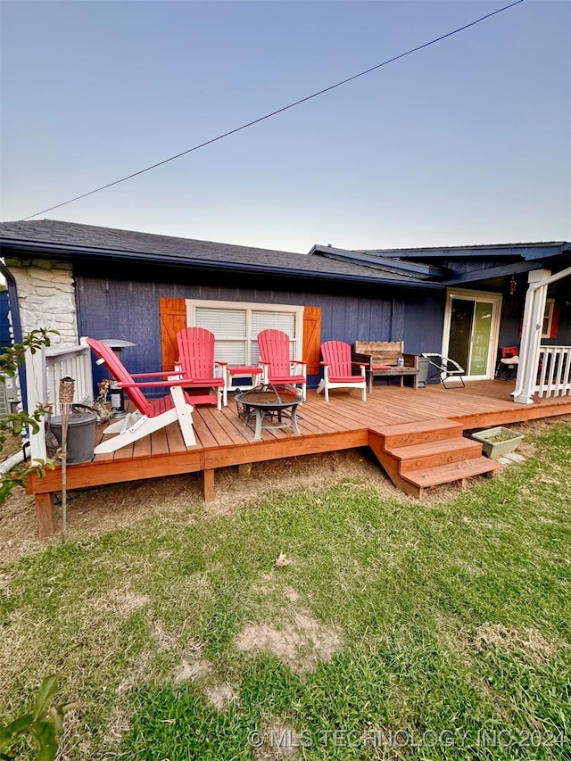 rear view of property with a wooden deck and a lawn