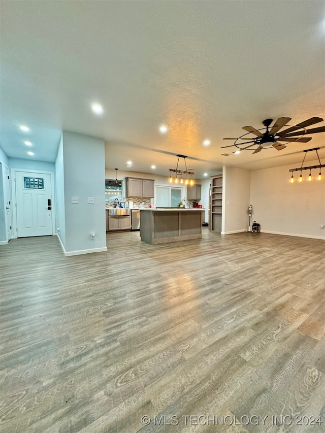 unfurnished living room featuring ceiling fan, hardwood / wood-style floors, and track lighting