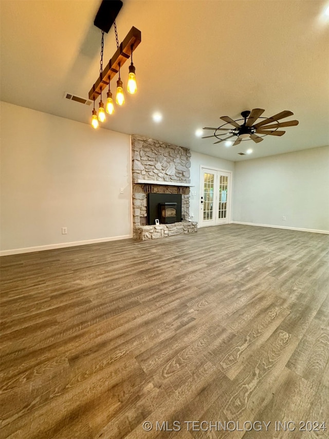 unfurnished living room featuring a fireplace, ceiling fan, hardwood / wood-style floors, and french doors