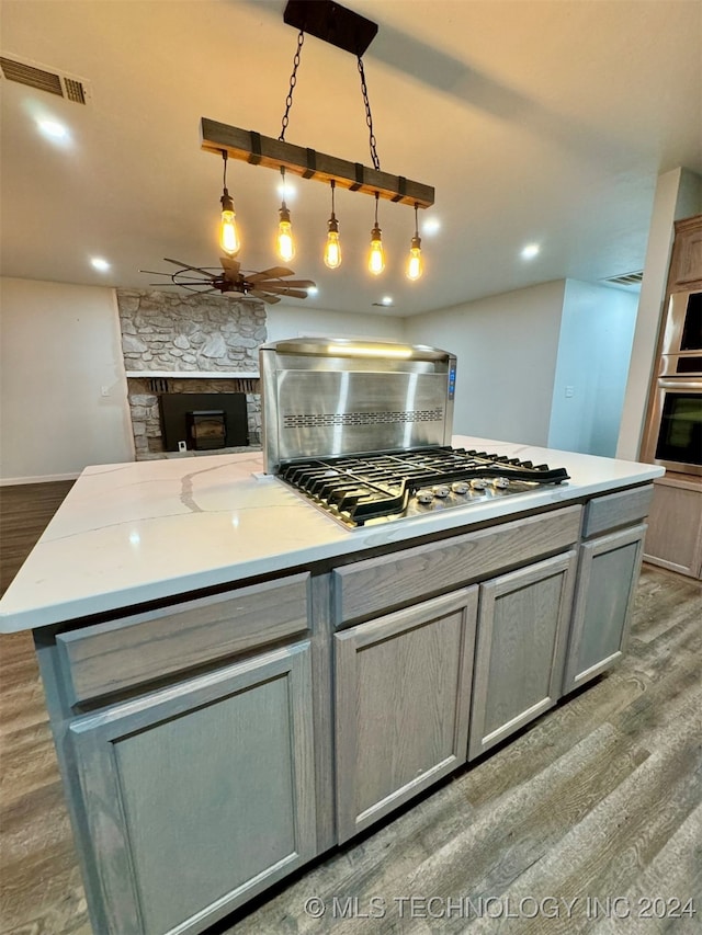 kitchen with ceiling fan, a fireplace, and hardwood / wood-style floors