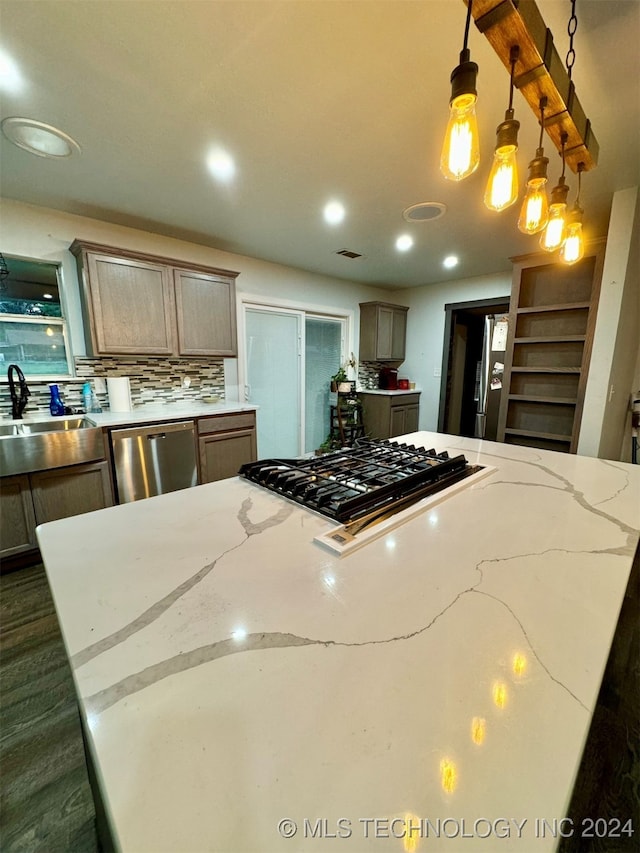 kitchen with sink, decorative light fixtures, decorative backsplash, light stone countertops, and dishwasher