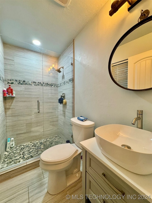 bathroom featuring toilet, walk in shower, vanity, and a textured ceiling