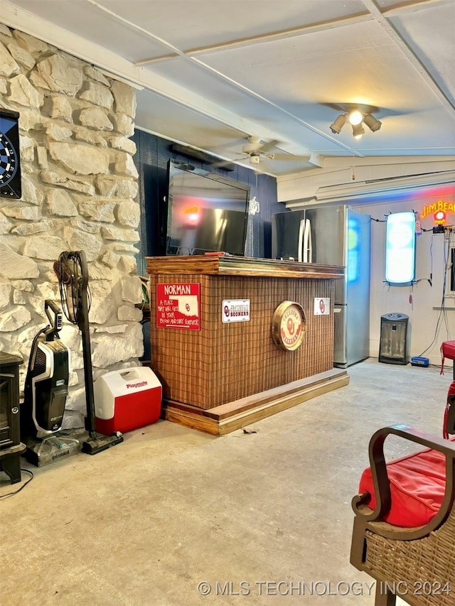 interior space featuring ceiling fan, stainless steel fridge, and concrete flooring