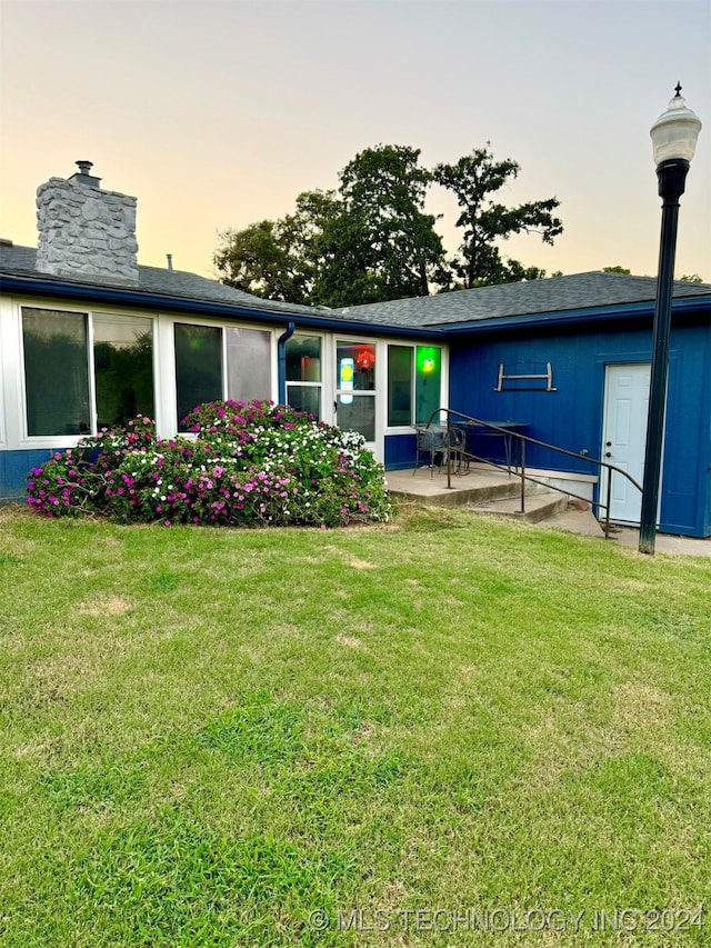 back house at dusk with a patio area and a yard